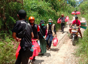 ACT staff delivering hot meals on foot to isolated villages (Majene, February 8, 2021)